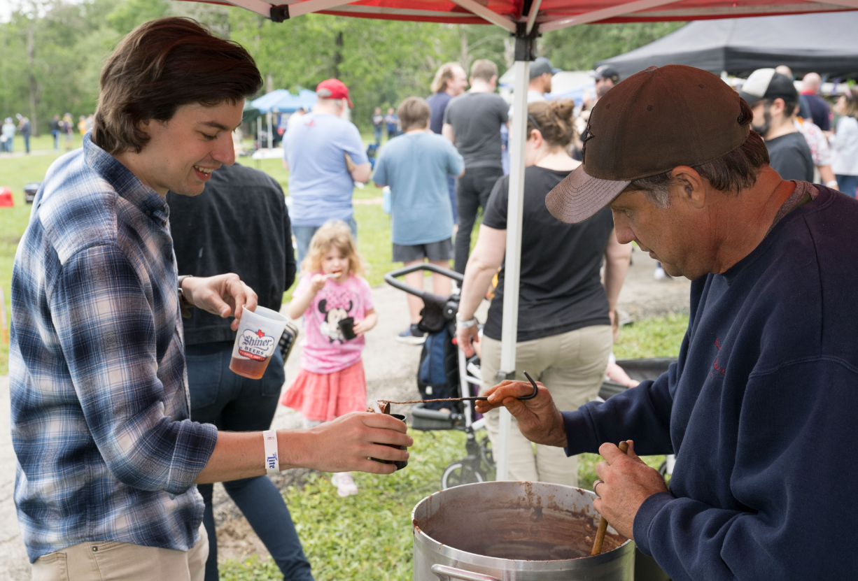 A cook pours chili into a cup for an event goer.